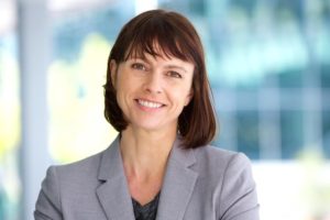 Confident middle-aged woman smiling, representing successful dental implant treatment.