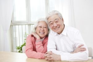 Elderly couple smiling together, representing satisfaction with full or partial dentures.